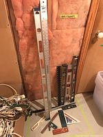 Photo showing assortment of levels and squares leaning against insulation and wall corner.
