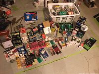 Wide view of assortment of light bulbs and lighting items spread on floor, showing variety of packages and loose bulbs.