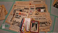 Photo showing a collection of old newspapers and magazines including The Globe and Mail, Canadian Magazine, and The Weekend Telegram along with some sports cards and a memorial coin.