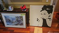 Shows two prints side by side with the Audrey Hepburn print on canvas and the Lake Louise print resting against the wall.