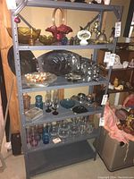 Front view of gray metal shelving unit with glassware on shelves