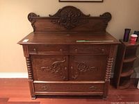 Full front view of carved oak sideboard with decorative backsplash, drawers, doors, and lower drawer