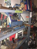Shelf with assorted tools including socket sets in case, screwdrivers, pliers, various loose hand tools, keys and hammers