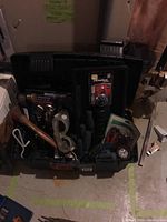 Full view of black toolbox filled with assorted hand tools and accessory items including a hammer, screwdrivers, safety goggles, and a lockbox.