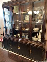 Front view of the large dark mahogany Asian hutch with glass doors showing displayed dishes and glassware inside.