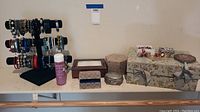 Full view of black velvet stand loaded with bracelets, Connoisseurs spray, multiple jewelry boxes and tray