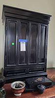 Closed black wooden altar with hinged panel doors, rectangular panelled decoration.