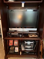 Full front view of the entertainment center showcasing the Vizio TV, stereo components, movies, and VHS tapes.