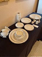 Full view of set including stacked dinner plates, salad plates, saucers, cups; the vase behind and four animal figurines in front