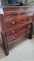 Front view of mahogany highboy dresser showing drawer configuration and original hardware with round wooden knobs and brass pulls.