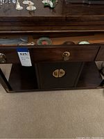 Front view of small Asian mahogany buffet showing one open drawer and cupboard doors beneath with Chinese style brass hardware.