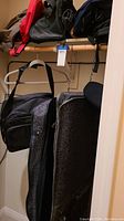 Photo showing garment bags and shoulder bags hanging on closet rod.