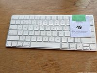 Top view of Apple wireless keyboard showing full QWERTY layout keys with white aluminum casing.