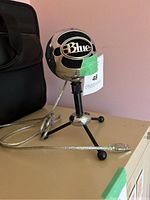 Front and side view of Blue Microphones Snowball microphone on black tripod stand with USB cable coiled beside it.
