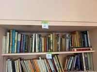 Two-shelf overview showing approximately 60 books of various sizes and colors
