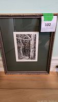 Framed glass artwork with the black and white print visible through the glass. Includes framing details and inventory tag.