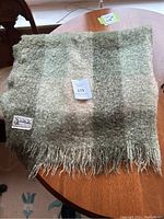 Full view of folded mohair throw blanket on table with visible Glen Cree label.