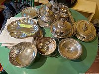 Full view of multiple silver plated pieces arranged on table including tureen, bowls, trays