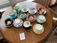 Overhead view of eleven assorted porcelain teacup and saucer sets on wooden table
