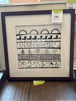 Framed 17x17 inch black and white Warli style art print showing rows of stylized animals, plants, and geometric patterns.