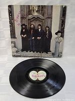 Front cover of Beatles Again LP showing the four band members standing in front of a wooden door and marble busts, with visible wear and handwritten markings.
