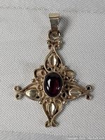 Close-up photo of sterling silver pendant front with symmetrical Art Nouveau filigree and central oval amethyst gemstone.