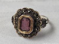 Front angled view of the sterling silver ring showing purple amethyst center and marcasite accents on scalloped setting.