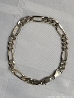 Full view of sterling silver thick link bracelet laid flat on fabric surface.