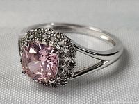Front angle of sterling silver ring with pink topaz and marcasite halo on white fabric