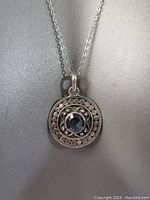 Close-up photo of the circular pendant with smokey topaz stone and detailed silverwork on the chain.