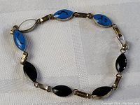Sterling silver jewelry piece featuring turquoise, mother of pearl and onyx stones with clasp shown.