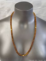 Full front view of vintage amber necklace on display bust, showing round translucent amber beads with one lighter butter amber bead towards front.