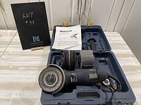 Angle grinder with discs, handle, manual, and case open on table