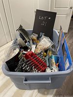 Top down view of gray plastic bin filled with various assorted tools including wrenches, clamps, clothespins, and boxed items.