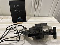 Image of the electric planer showing the device, power cord, and handle on a white surface with a sign indicating lot number.