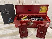 Red toolbox open showing assorted hand tools inside, two red saw horse brackets in front.