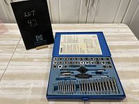 Full view of the open blue metal case containing multiple taps, dies, and handles neatly arranged with a label inside the lid.