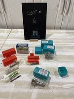 Overall lot of multiple tipped drill bits in red and blue plastic cases on white surface