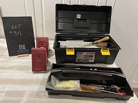 Strong N' Tuff black plastic toolbox opened showing removable tray with tools and two red metal sawhorse brackets next to it.
