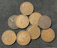 Top view of ten old copper coins placed on a dark surface to show detailed obverse and reverse sides with various monarch profiles and emblematic designs.