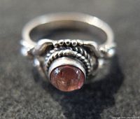 Front view showing vintage sterling silver ring with a round reddish cabochon gemstone and detailed silver setting.
