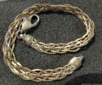 Vintage sterling silver tri-coloured twisted rope bracelet laid flat on black background showing detail of chains and clasp.
