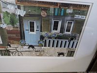 Close-up photo of the paper collage artwork showing details of the Quebec City street scene with three black cats, blue door, and flowers.