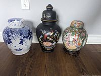 Front view of all three jars - black glass, blue and white ceramic, and rose medallion ceramic