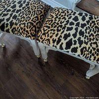 Top view of two wicker stools showing leopard print upholstery and wicker legs