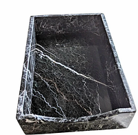 Top-down angled view of the rectangular black marble paper tray showing white veins and corner chip