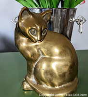 Front and side view of the brass cat figurine showing smooth polished surface with some minor wear and small patina details.