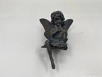 Front view of the vintage angel figurine sitting with one leg extended, showing detailed wings and floral crown.