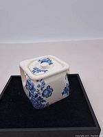 Photo showing the square box-shaped teapot with blue floral pattern on a white base, viewed front and left side with lid on.