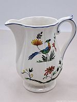 Full view of GIEN porcelain ceramic pitcher with curved spouted rim and handle, featuring colorful bird and flower painted design.